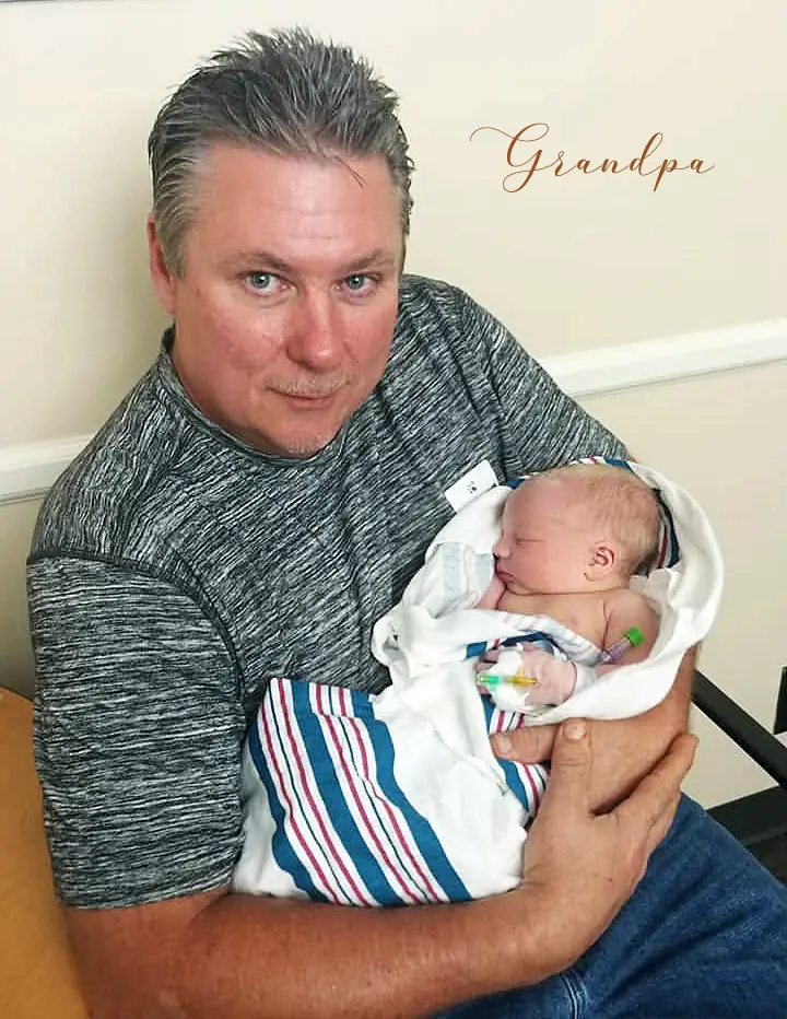 Photo of Bobby, the CEO and founder of Fire Mountain Candles holding a his newborn grand-baby.